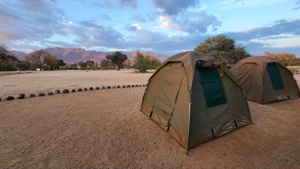 A landscape image of 2 camping safari tents with Brandberg massif in the background